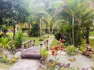 a wooden bridge in a garden with palm trees at Najjamee Bungalows in Ko Yao Noi