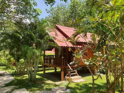 a house with a bench in the middle of trees at Najjamee Bungalows in Ko Yao Noi