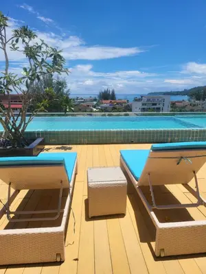 a patio with two lounge chairs and a swimming pool at Ratana Platinum Resort Kamala in Kamala Beach