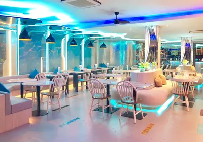 a restaurant with tables and chairs and blue lights at Ratana Platinum Resort Kamala in Kamala Beach