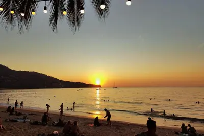a group of people on the beach at sunset at Ratana Platinum Resort Kamala in Kamala Beach