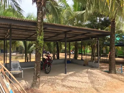a motorcycle parked under a pavilion with a palm tree at Suan Proud Koh yao noi in Ko Yao Noi