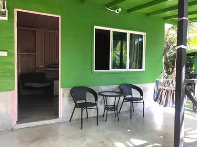 a green house with chairs and a table in front at Suan Proud Koh yao noi in Ko Yao Noi