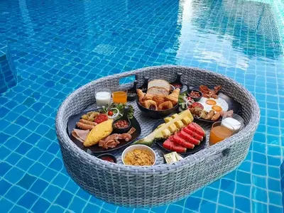 a tray of breakfast food in a wicker basket by a swimming pool at BlueSotel SMART Krabi Aonang Beach - Adults only in Ao Nang Beach