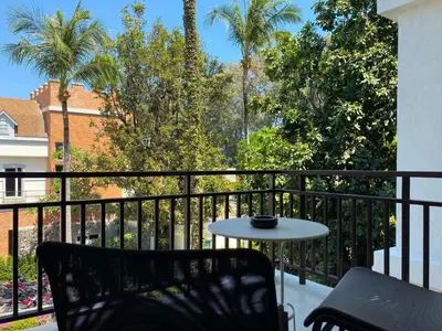 a table and chair on a balcony with palm trees at Title Rawai Phase III by Beringela in Rawai Beach