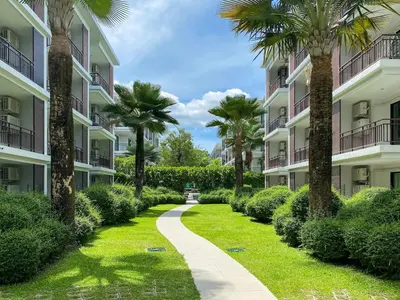 a walkway between two apartment buildings with palm trees at Title Rawai Phase III by Beringela in Rawai Beach