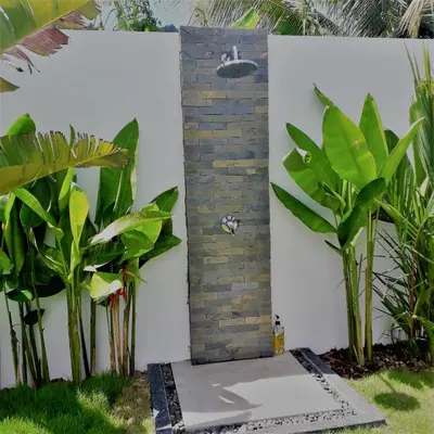 a bathroom with plants in front of a brick wall at Villa KHAO MANEE in Nai Yang Beach