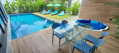 a glass table and chairs next to a swimming pool at Villa KHAO MANEE in Nai Yang Beach