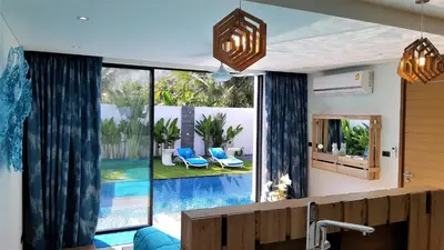 a living room with a large window with a swimming pool at Villa KHAO MANEE in Nai Yang Beach