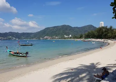 a beach with a boat in the water at Patong Karlssons Hotel in Patong Beach