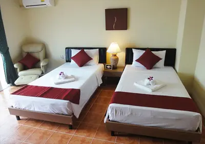 a bedroom with two beds and a chair at Patong Karlssons Hotel in Patong Beach