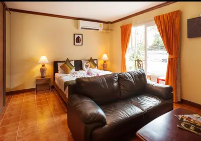 a living room with a leather couch and a bed at Patong Karlssons Hotel in Patong Beach