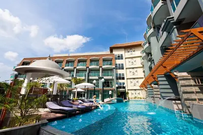 a pool at a hotel with chairs and umbrellas at Ramaburin Resort Patong - SHA Extra Plus in Patong Beach