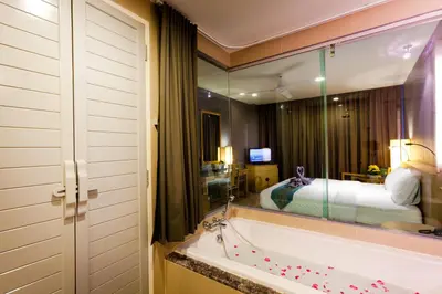 a bathroom with a tub and a bed and a mirror at Ramaburin Resort Patong - SHA Extra Plus in Patong Beach