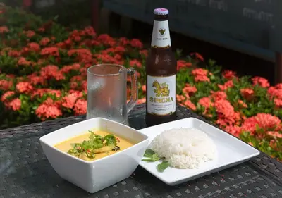 a bottle of beer and a bowl of food and rice at Tropical Sands in Nai Harn Beach