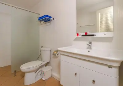 a white bathroom with a toilet and a sink at Tropical Sands in Nai Harn Beach