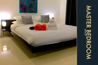 a bedroom with a bed with two red objects on it at 3 BR Amazing Condo with Private Rooftop Pool in Kamala Beach