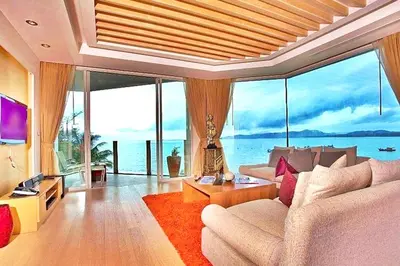 a living room with a couch and large windows at Warm Apartment in Ban Chai Nam, 180 m² with Jacuzzi in Surin Beach