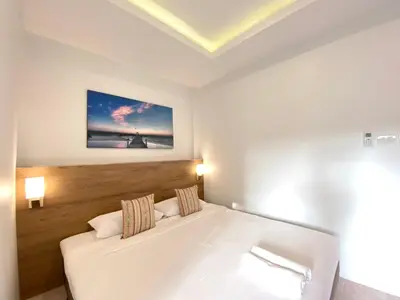 a bedroom with a white bed and a painting on the wall at Pensiri House - SHA Extra Plus in Nai Yang Beach