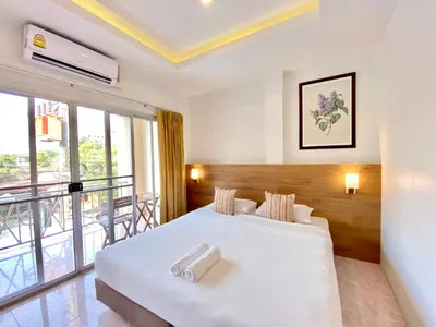 a bedroom with a large white bed and a balcony at Pensiri House - SHA Extra Plus in Nai Yang Beach