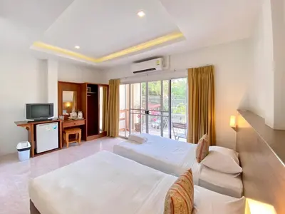 a hotel room with two beds and a television at Pensiri House - SHA Extra Plus in Nai Yang Beach