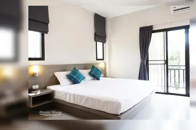 a bedroom with a white bed with blue pillows at Pensiri House - SHA Extra Plus in Nai Yang Beach