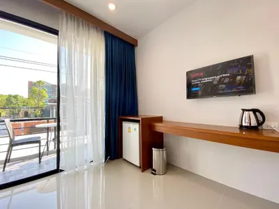 a living room with a large window and a table and chair at Pensiri House - SHA Extra Plus in Nai Yang Beach