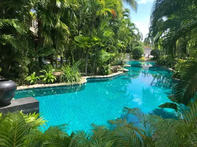 a pool in a resort with blue water and palm trees at Villa on The Rocks, 4 bedrooms, Phuket in Surin Beach