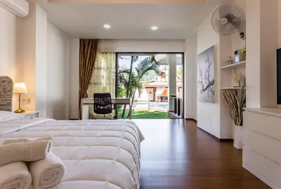 a bedroom with a bed and a table with a chair at Villa Status in Nai Harn Beach