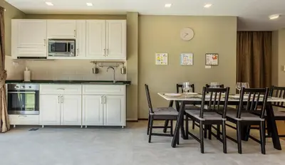 a kitchen with white cabinets and a table and chairs at Villa Status in Nai Harn Beach