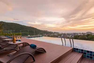 a swimming pool with chairs and a table on a deck at Splendid Sea View Resort in Kata Beach