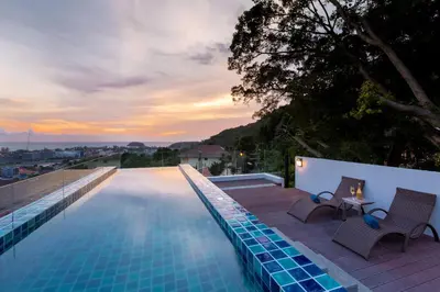 a swimming pool with two chairs and a table on a building at Splendid Sea View Resort in Kata Beach