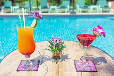 two drinks on a table next to a pool at Harmony Naturist Resort Rawai Phuket 18yr minimum age only nudist nake d FKK in Rawai Beach