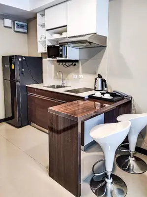 a kitchen with a counter and two stools in it at MBC Mai Khao Beach Condotel LUXURY APARTMENTs in Phuket Town