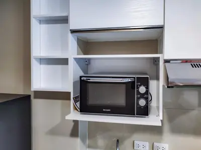 a microwave in a kitchen with white cabinets at MBC Mai Khao Beach Condotel LUXURY APARTMENTs in Phuket Town