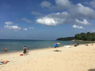 a group of people on a beach with an umbrella at Best Point Condominium Cape Panwa in Phuket Town