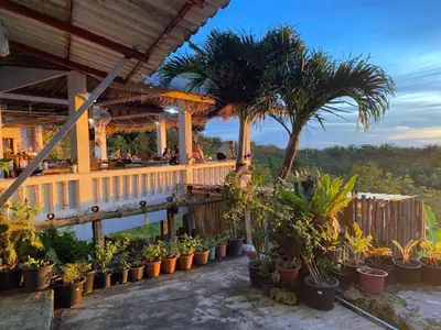 a restaurant with palm trees and plants on a deck at Best Point Condominium Cape Panwa in Phuket Town