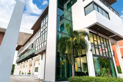 an office building with large windows and palm trees at The Thames Pool Access Resort & Villa - SHA Extra Plus in Chalong