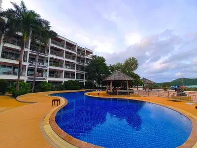 a large swimming pool with a gazebo next to a building at Spacious apartment with Ocean view in Panwa in Phuket Town