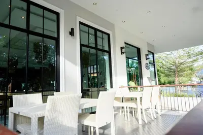 a patio with white chairs and tables and windows at Rnana Grand in Phangnga