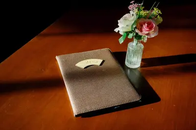 a notebook and a vase of flowers on a table at Rnana Grand in Phangnga