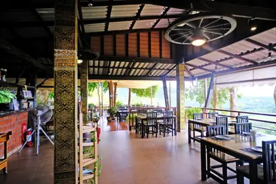 a restaurant with tables and chairs in a room at Rnana Grand in Phangnga