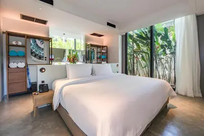 a bedroom with a large white bed and a large window at Island Escape Burasari in Phuket Town