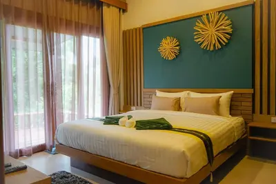 a bedroom with a large bed with yellow walls and windows at Thap Kaek B2 Villa in Klong Muang Beach