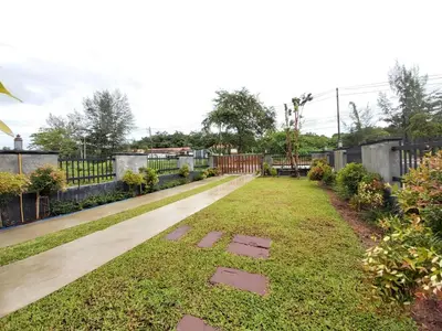 a garden withestones in the grass next to a fence at Thap Kaek B2 Villa in Klong Muang Beach