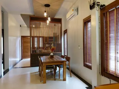 a dining room with a wooden table and some windows at Thap Kaek B2 Villa in Klong Muang Beach