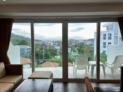 a living room with a large sliding glass window at Kata Ocean View condominium by Lofty in Kata Beach