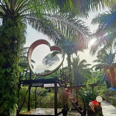 a mirror in the shape of a heart in a garden at Koom Kachanaan in Ban Nong Thale
