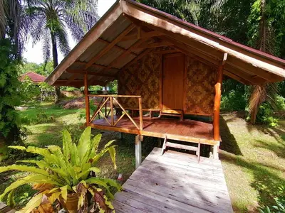 a cabin with a wooden porch with a roof at Koom Kachanaan in Ban Nong Thale
