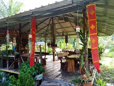 a wooden deck with a tent with tables and plants at Koom Kachanaan in Ban Nong Thale